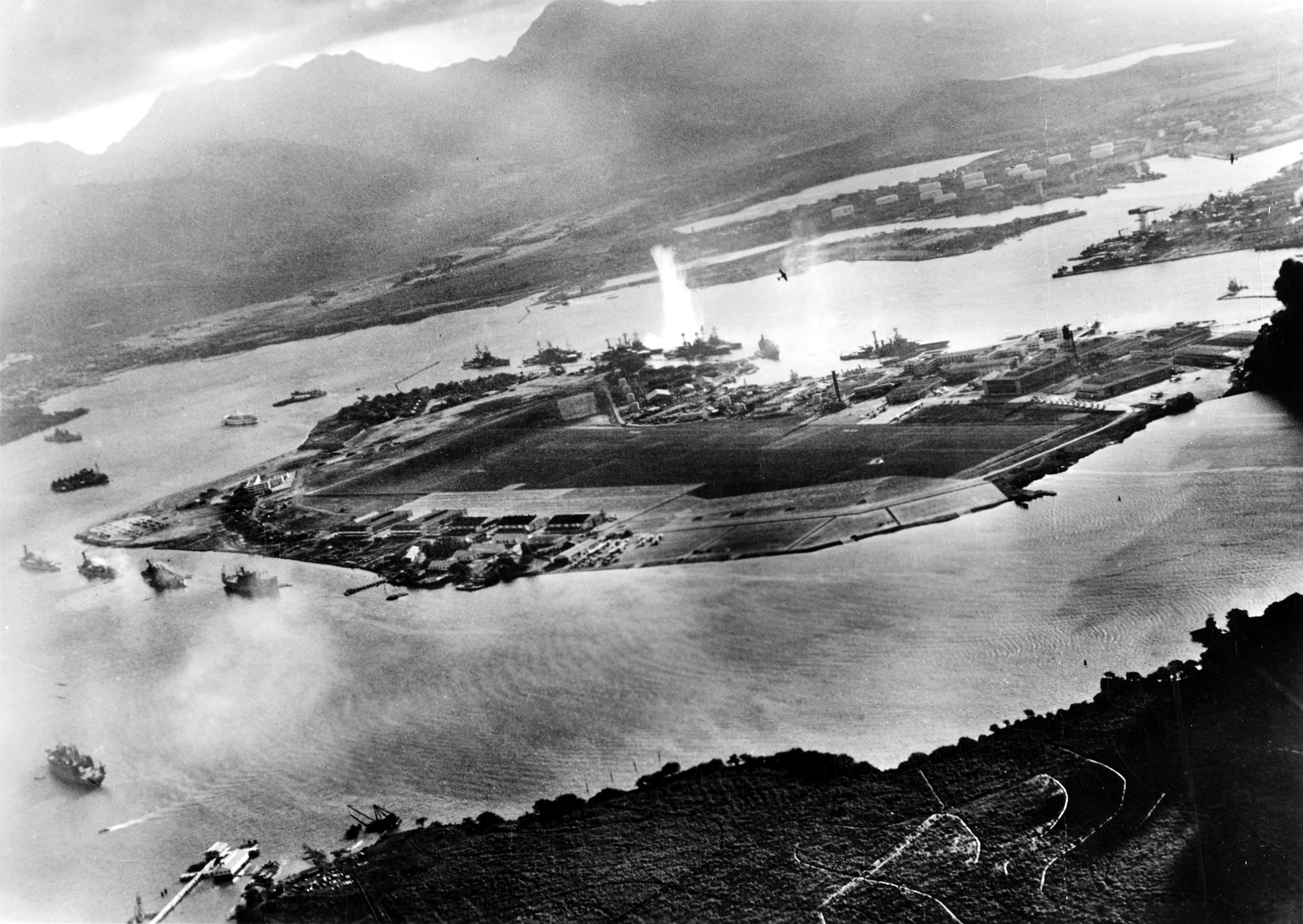 Aerial view of Pearl Harbor during the Japanese attack, with smoke rising from battleships